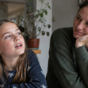 Mutter und Tochter sitzen gemeinsam am Tisch und sprechen miteinander