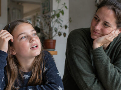 Mutter und Tochter sitzen gemeinsam am Tisch und sprechen miteinander