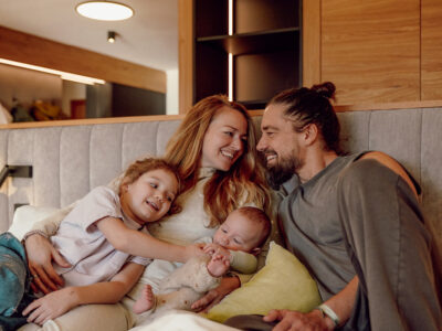 Familie mit zwei Kindern entspannt gemeinsam auf einem Bett in der Ferienwelt Kesselgrub