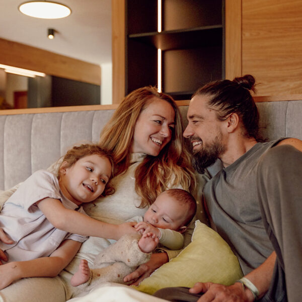 Familie mit zwei Kindern entspannt gemeinsam auf einem Bett in der Ferienwelt Kesselgrub